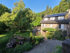 an old stone house with a garden in front of it at Gîte du moulin de Tanis in Oisseau