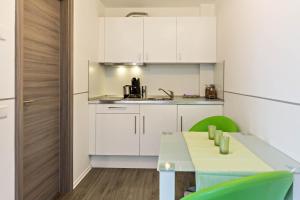 a kitchen with white cabinets and a table and green chairs at Apartment 4 in Rielasingen-Worblingen