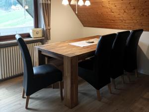 a dining room table with black chairs and a wooden table at Ferienwohnung Wiesenblick in Oberharmersbach +3 photos