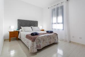 a white bedroom with a bed and a window at Casa Dragos in Costa Teguise