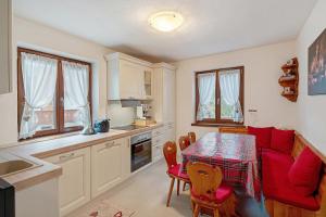 a kitchen with a table and a red couch in a kitchen at Ciasa Civetta in Piaia