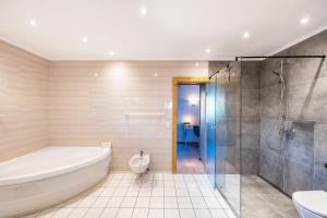 a bathroom with a tub and a shower and a toilet at Haus am Bach in Benediktbeuern +41 photos