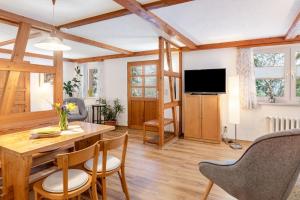 a living room with a table and chairs and a television at Ferienwohnung Am Schleifenbach 2 in Saalfeld