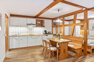 a kitchen with white cabinets and a wooden table and chairs at Ferienwohnung Am Schleifenbach 2 in Saalfeld
