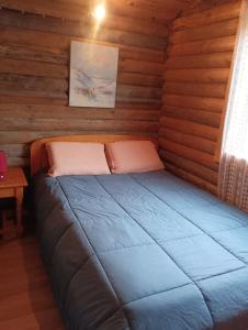 a bed in a log cabin with a window at Chalet Idéal Randonnée in La Chapelle-Yvon