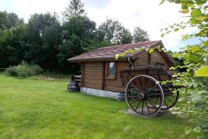 a small wooden cabin with a wagon in the grass at Chalet Idéal Randonnée in La Chapelle-Yvon