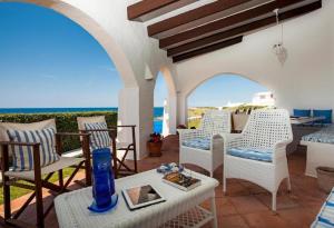 a patio with chairs and a table and the ocean at Villa Bini Sek in Binibeca