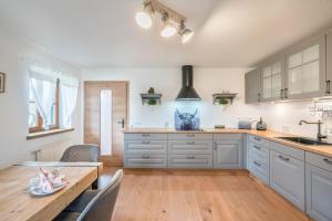 a kitchen with white cabinets and a wooden table at Wohnung Sonntraten in Gaißach