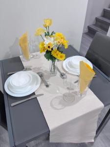 a table with white plates and yellow flowers on it at Cozy Home basement suite with private separate entrance in Winnipeg