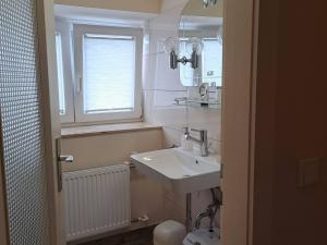 a white bathroom with a sink and a window at Algetet Apartment in Hannover +13 photos