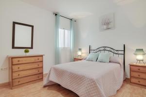 a bedroom with a bed and a dresser and two lamps at Piso Ana Paula 1 in Conil de la Frontera