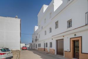 a white building with a car parked on a street at Piso Ana Paula 1 in Conil de la Frontera
