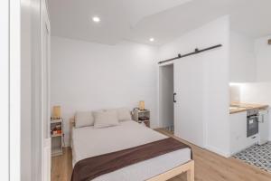a white bedroom with a bed and a kitchen at Portblanc Loft in Arenys de Mar