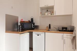 a small kitchen with white cabinets and a microwave at Le Castel in Marseille
