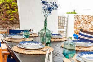 a table with plates and a vase with flowers in it at Alojamiento con encanto in Binibeca