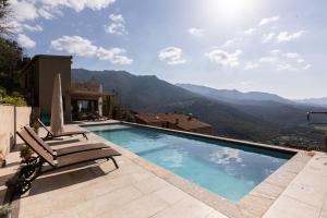 a swimming pool with chairs and a view of mountains at A Chiusella in Belgodère