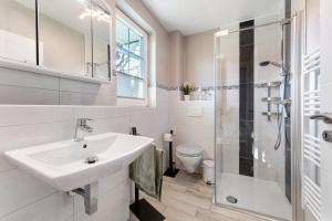 a white bathroom with a sink and a shower at Feriendoppelhaus Frühling in Stakendorf +20 photos