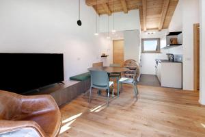 a living room with a table and chairs and a television at Violet a due passi da Bormio in Valdidentro