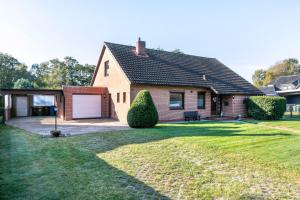 a house with a garage and a grass yard at Dörpshus in Rehm-Flehde-Bargen