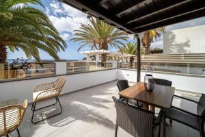 a balcony with a table and chairs and palm trees at Callao in Playa Honda