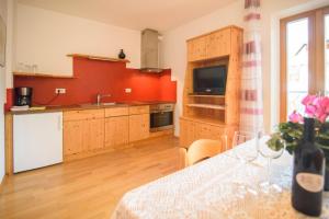 a kitchen with red walls and wooden cabinets and a table at Peter Paul Terrassenapp Hocheppan in Appiano Sulla Strada Del Vino