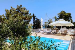 a pool with chairs and a table and an umbrella at Euphoria Apartments in Lixouri