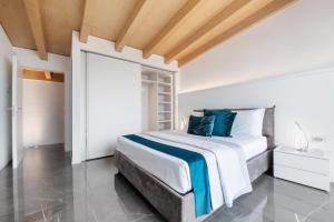 a white bedroom with a bed and a wooden ceiling at Luxury Lakefront Penthouse in Lezzeno