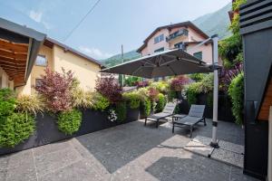 a patio with two chairs and an umbrella at Luxury Lakefront Penthouse in Lezzeno