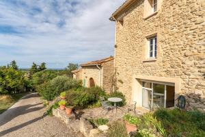 an external view of a stone house with a table and chairs at Les Conils in Saint-Pierre-de-Vassols