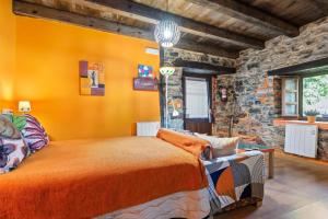 a bedroom with an orange bed and a stone wall at Loureiro in Vega de Logares