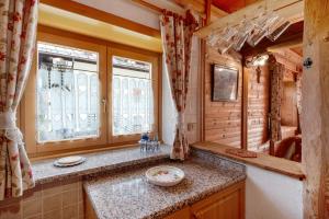 a kitchen with a counter and a window in a log cabin at Appartamenti Marmolada Falcade in Falcade +57 photos
