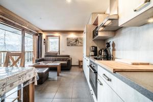 a kitchen and living room with a couch and a table at Les loges blanches204 centre chatel in Châtel