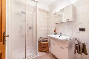 a white bathroom with a shower and a sink at Appartement Annie in Nova Ponente +13 photos