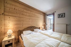a bedroom with a large bed with a wooden wall at Les loges blanches204 centre chatel in Châtel