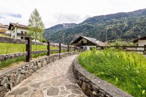 a stone path with a fence and mountains in the background at Appartamento Collini Le Betulle in Spiazzo
