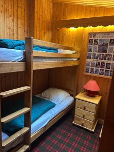 a bedroom with two bunk beds and a table with a lamp at Duplex Méribel Mottaret 8 personnes in Les Allues