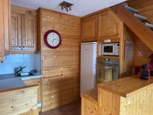 a kitchen with wooden cabinets and a clock on the wall at Duplex Méribel Mottaret 8 personnes in Les Allues +7 photos
