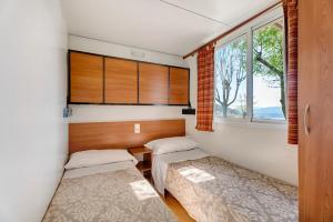 two beds in a room with two windows at Camping Royal in Pettenasco +48 photos
