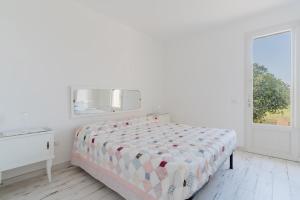 a white bedroom with a bed and a mirror at Dimora Balu' in Parabita