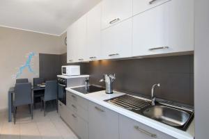 a kitchen with white cabinets and a sink and a table at Colico Center in Colico