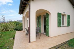 a house with green shutters and a patio at Appartamento Vallebona in Seborga