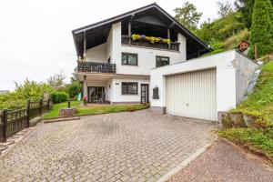 a white house with a balcony and a driveway at Ferienwohnung Klug in Haintchen