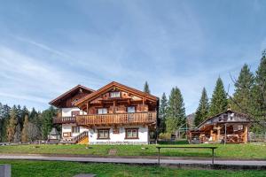 a large wooden house in the middle of a field at Appartamenti Marmolada Falcade in Falcade