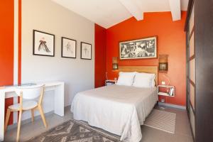 a bedroom with orange walls and a bed and a desk at Maisonnette indépendante in Cassis