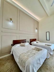 two beds in a room with white walls at Hotel Catedral in Cuernavaca