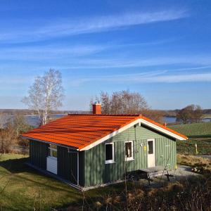 a green house with an orange roof in a field at Skipper-Lodge Ost in Kosel