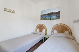 two beds in a room with white walls at Appartamenti Bonalaccia in Campo nell'Elba +81 photos