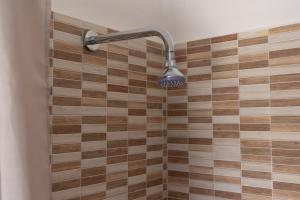 a shower with a shower head on a tiled wall at Dimora Home Sweet Home with Private Pool in Putignano