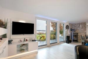 a living room with a tv and sliding glass doors at Häuser am See in Königs Wusterhausen