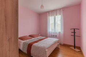 a bedroom with a bed with pink walls and a window at Le Pin Franc in Valeyrac